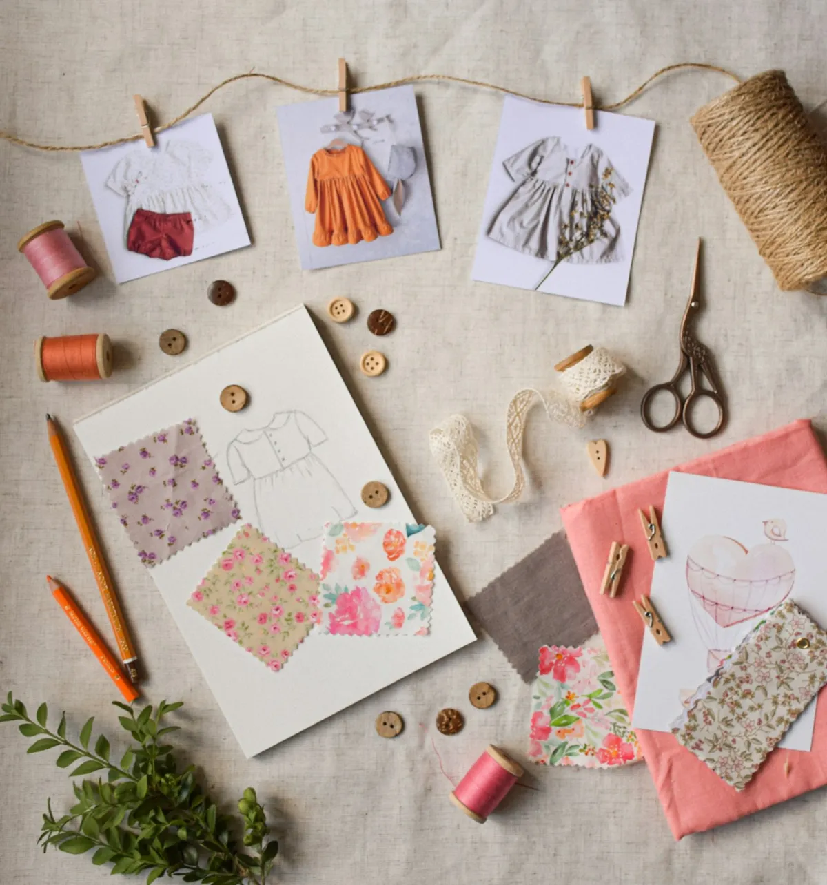 Wedding dress design sketch with fabric swatches and thread spools on a linen work table